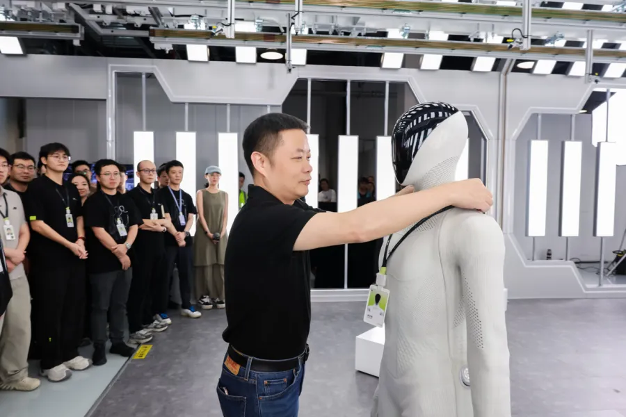 He Xiaopeng standing beside the IRON humanoid robot in front of XPeng employees